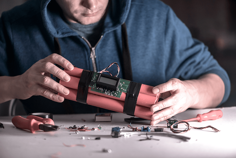 A person is assembling an electronic device that resembles a makeshift explosive.