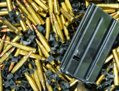 The image shows a pile of ammunition cartridges and an empty magazine.