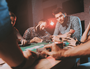 A group of people is intently engaged in a game of poker around a table with cards and chips in hand.