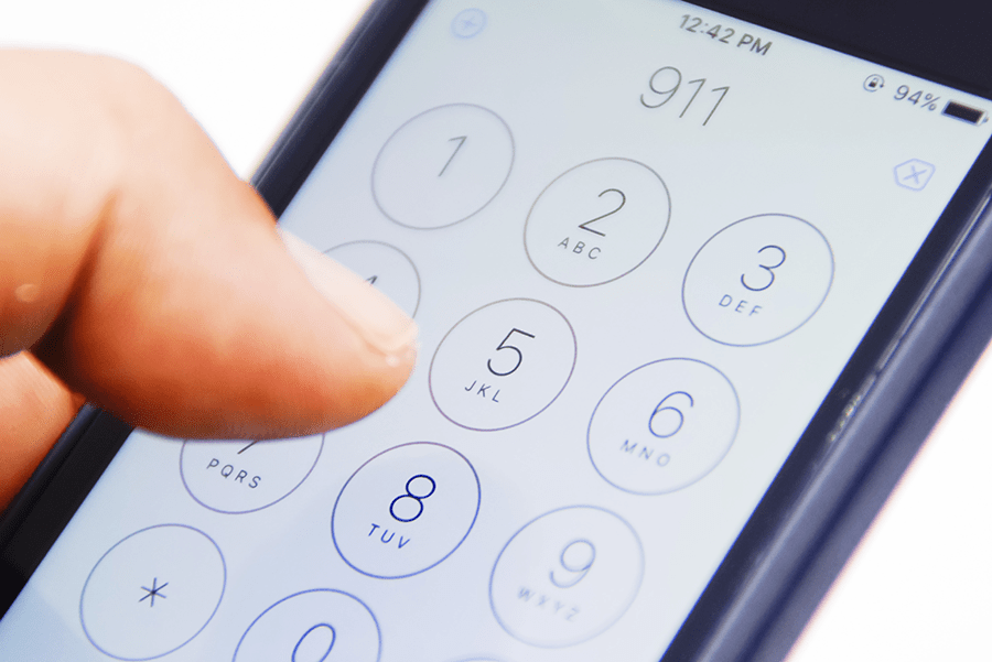 A person's thumb is dialing a number on a smartphone's touch keypad with a visible time and battery percentage at the top of the screen.