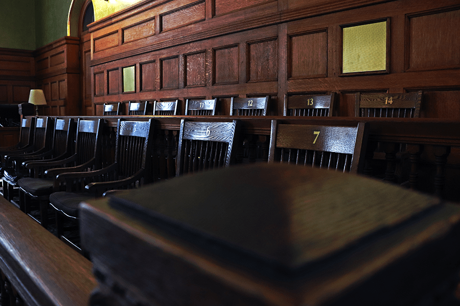 Wooden jury box with numbered seats in a traditional courtroom setting.