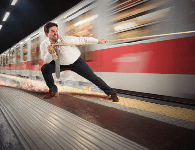 A man is pretending to pull a rapidly moving train at a subway station.