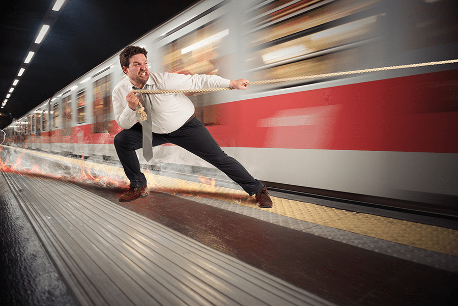 A man is pretending to pull a rapidly moving train at a subway station.