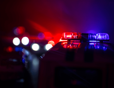An emergency vehicle's flashing red and blue lights are illuminated against a dark, out-of-focus background.