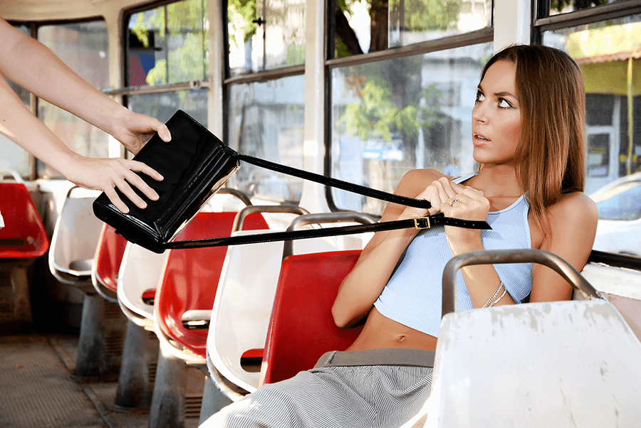 A woman on a bus is clutching her purse as another person tries to snatch it away from her.