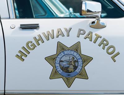 The image shows the door of a white California Highway Patrol car with the agency's emblem.